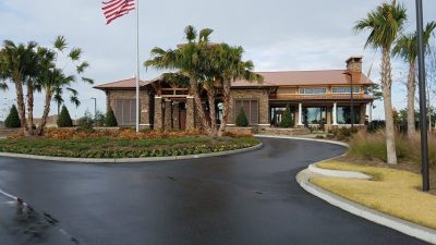 The Lodge clubhouse with palm trees and flowers in front